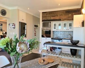 uma cozinha com armários brancos e uma mesa num quarto em Apartment18Lifestyle Gordons Bay Beachfront em Gordonʼs Bay