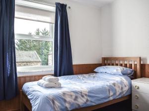 a bedroom with a bed with blue curtains and a window at Uk39800 - Crag Barn in Troutbeck