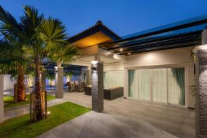 a house with a patio with palm trees in it at Orchid Paradise Homes OPV428 in Hua Hin
