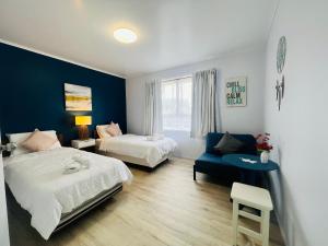 1 dormitorio con 2 camas y pared azul en La Sol - All you need for a stay, close to town, University & Cambridge, en Hamilton
