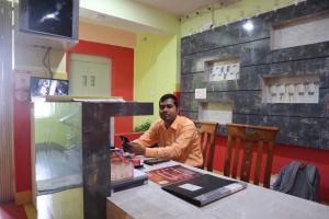 Ein Mann, der an einem Tisch in einem Restaurant sitzt. in der Unterkunft Hotel Saan Berhampore in Baharampur