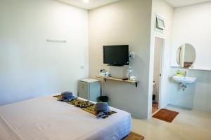 a room with a bed and a tv and a bathroom at My Home Lantawadee Resort in Ko Lanta