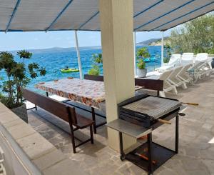 a patio with a table and a grill and the ocean at Group Holiday Accommodation Natura Croatia, Sleeps Up To 13 People in Maslenica