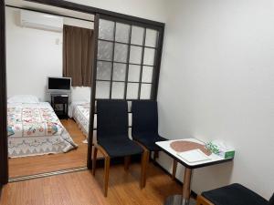 大阪市にあるMarunishiのベッド、テーブル、椅子が備わる小さな客室です。
