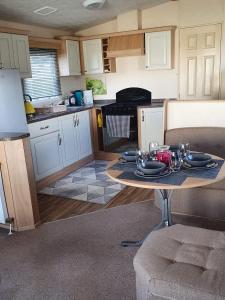 a kitchen with a table with plates and glasses on it at STATIC CARAVAN N WALES LyonsRobinHood RHYL in Meliden