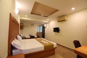 a hotel room with a bed and a desk at Hotel Rydham in Madurai