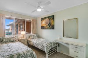 Un dormitorio con dos camas y un televisor y una ventana. en Beach Lodge Unit 12a, en Gold Coast