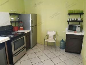 Casa Tecalai 5 في سان كارلوس: مطبخ مع ثلاجة وموقد وكرسي