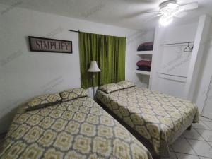 1 dormitorio con 2 camas y cortina verde en Casa Tecalai 5, en San Carlos