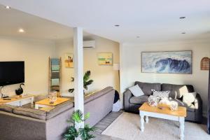 een woonkamer met een bank en een tafel bij Swanway family holiday home - 15 min walk to beach, seconds to lake in Culburra Beach