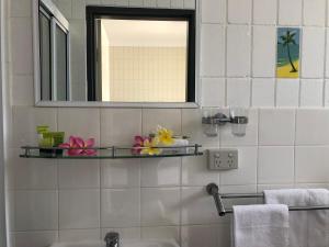 a bathroom with a mirror and a sink at Tropical Palms Resort & 4WD Hire in Picnic Bay +22 photos