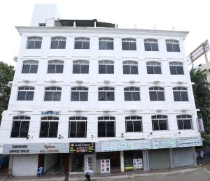 a white building with people walking in front of it at Hotel Rydham in Madurai