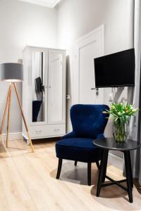 a living room with a blue chair and a table at Househost Apartment: Bonerowska 5/15 in Krakow