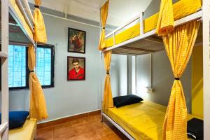 - une chambre avec 2 lits superposés et des rideaux jaunes dans l'établissement Whoopers hostel Palolem, à Palolem