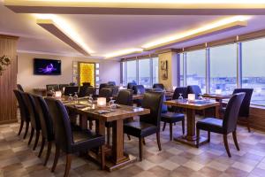 un ristorante con tavoli, sedie e ampie finestre di Wakra Inn Hotel Apartments a Al Wakrah