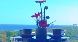 een tafel met drie kopjes en een vaas met bloemen bij Mactan Newtown - New Modern Condo with Ocean View in Mactan