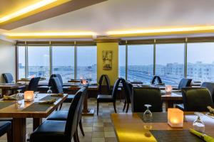 un ristorante con tavoli, sedie e ampie finestre di Wakra Inn Hotel Apartments a Al Wakrah