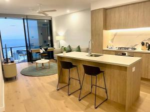 a kitchen with a sink and a counter with bar stools at Broadbeach Luxury OceanView 2beds apartment 49F in Gold Coast