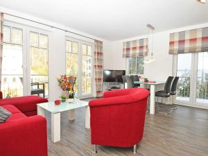 a living room with red chairs and a table at Villa Rosa - Apt. 05 in Ostseebad Sellin