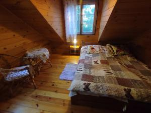 a bedroom with a bed in a wooden cabin at Rajski Staw in Zajki