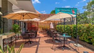 an outdoor patio with tables and chairs with umbrellas at Regantris Surabaya in Surabaya