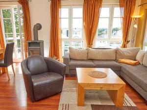 ein Wohnzimmer mit einem Sofa, einem Stuhl und einem Tisch in der Unterkunft Villa Sommerwind - WG 01 mit Sauna, Kamin und Terrasse in Ostseebad Sellin