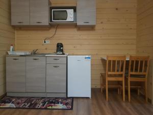 a kitchen with a refrigerator and a table and a microwave at Muskátli Apartman in Bogács