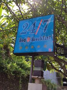 a blue sign for a bed and breakfast at 24/7 Bed & Breakfast in Jimbaran