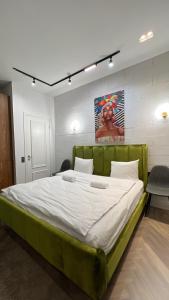 duże łóżko w pokoju z zieloną ramą w obiekcie Manica Esentai City w mieście Ałma-Ata
