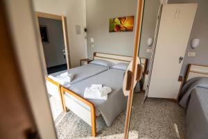 a small bedroom with a bed and a mirror at Hotel Ausonia in Rimini