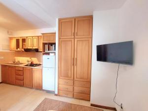 uma cozinha com armários de madeira e uma televisão de ecrã plano na parede em Beach Garden Studio em Cap Malheureux