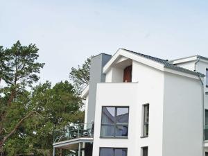 a white house with a balcony on the side of it at Strandvilla Baabe - Maisonette "Sonnenwiege" mit Sauna und Whirlpool in Baabe