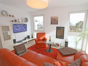 sala de estar con muebles de color naranja y TV en Strandvilla Baabe F 635 WG 26 mit Meerblick, Kamin, Sauna, Whirlpool en Baabe
