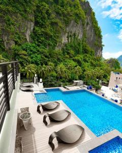 a swimming pool with chaise lounge chairs next to a mountain at Lagùn Hotel in El Nido