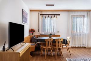 een woonkamer met een eettafel en een tv bij Villa Erina App A2 in Ortisei