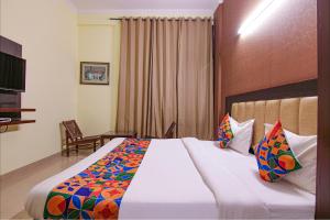 um quarto de hotel com uma cama grande com almofadas coloridas em FabHotel Town Pride em Sohāna
