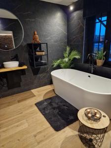 a bathroom with a white tub and a black wall at Suite Tino in Verviers