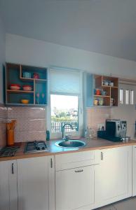 a kitchen with white cabinets and a sink and a window at Domek Na Ustroniu in Sasino