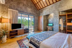 a bedroom with a large bed and a television at Leafy Home Canggu in Canggu