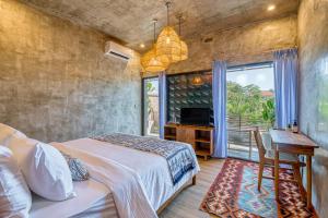 a bedroom with a bed and a desk and a window at Leafy Home Canggu in Canggu