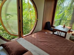 a bedroom with a bed in a room with large windows at InnerZen Riverside homestay Ben Tre - Japanese style in Ấp Phú Hòa (3)