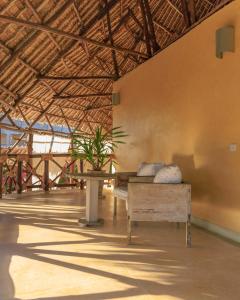 ein Zimmer mit einer Bank und einem Tisch in einem Gebäude in der Unterkunft Mawe Zuri Resort in Watamu
