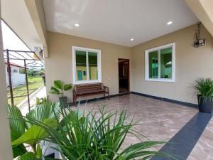 a porch with a bench and some plants at NurHumaira Homestay in Pantai Cenang