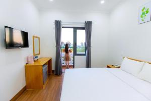 a hotel room with a bed and a woman looking out the door at Hotel Phạm Gia Phan Thiết in Phan Thiet