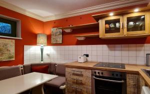 eine Küche mit orangefarbenen Wänden und einem Herd mit Backofen in der Unterkunft Art-House Kurort Rathen in Kurort Rathen