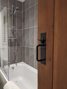 ein Badezimmer mit einer Dusche und einer Badewanne mit einer Tür in der Unterkunft Baker's Cottage, Urban Spa and Garden Bar in Evesham