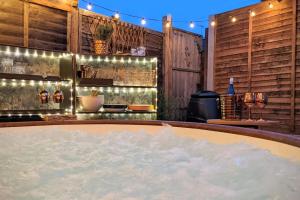 eine Badewanne mit Schnee neben einer Bar mit Lichtern in der Unterkunft Baker's Cottage, Urban Spa and Garden Bar in Evesham