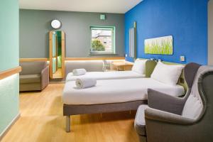 シェフィールドにあるイビス バジェット シェフィールド アリーナのベッド2台とソファが備わる客室です。