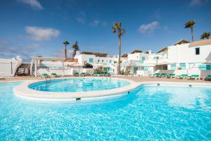 Una gran piscina con agua azul frente a edificios blancos. en Smy Tahona Fuerteventura, en Caleta de Fuste