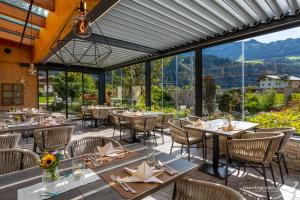 a restaurant with tables and chairs with mountains in the background at Ferienhotel Sonnenhof in Zell am Ziller